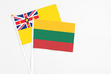 Lithuania and Niue stick flags on white background. High quality fabric, miniature national flag. Peaceful global concept.White floor for copy space.