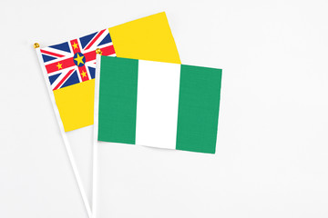Fototapeta premium Nigeria and Niue stick flags on white background. High quality fabric, miniature national flag. Peaceful global concept.White floor for copy space.
