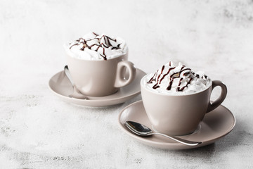 Two cups of coffee with whipped cream and chocolate topping. Iced coffee in white cup isolated on...