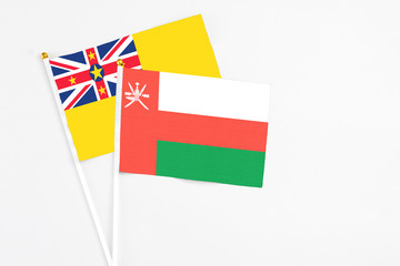 Oman and Niue stick flags on white background. High quality fabric, miniature national flag. Peaceful global concept.White floor for copy space.