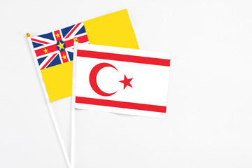 Northern Cyprus and Niue stick flags on white background. High quality fabric, miniature national flag. Peaceful global concept.White floor for copy space.