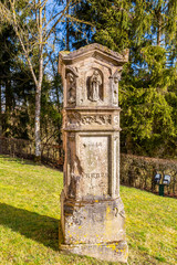 Fototapeta na wymiar Beautiful old tombstone in the churchyard of the Church of St. Maximin, village of Pintsch, Commune of Kiischpelt, Northern Luxembourg