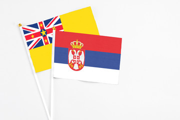Serbia and Niue stick flags on white background. High quality fabric, miniature national flag. Peaceful global concept.White floor for copy space.