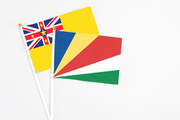 Seychelles and Niue stick flags on white background. High quality fabric, miniature national flag. Peaceful global concept.White floor for copy space.