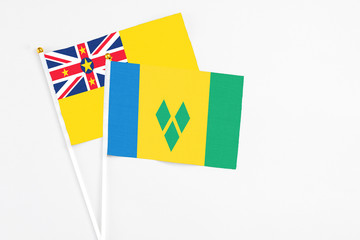 Saint Vincent And The Grenadines and Niue stick flags on white background. High quality fabric,...