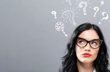 Question marks with young businesswoman in a thoughtful face