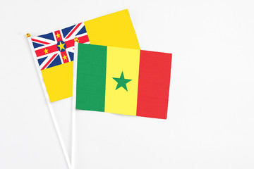 Senegal and Niue stick flags on white background. High quality fabric, miniature national flag. Peaceful global concept.White floor for copy space.