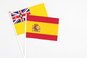 Spain and Niue stick flags on white background. High quality fabric, miniature national flag. Peaceful global concept.White floor for copy space.