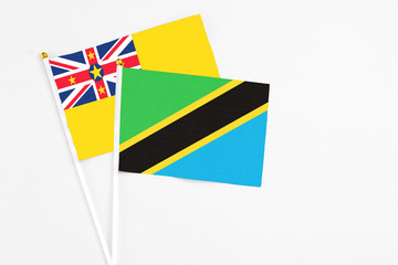 Tanzania and Niue stick flags on white background. High quality fabric, miniature national flag. Peaceful global concept.White floor for copy space.
