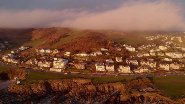 Dramatic Aerial Landscape Woolacombe Village, Rocky Coast With Clouds Sitting Over Hills In Winter At Sunset