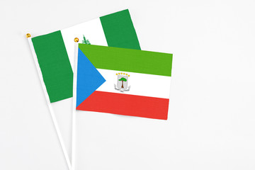 Equatorial Guinea and Norfolk Island stick flags on white background. High quality fabric, miniature national flag. Peaceful global concept.White floor for copy space.