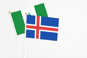 Obraz premium Iceland and Norfolk Island stick flags on white background. High quality fabric, miniature national flag. Peaceful global concept.White floor for copy space.