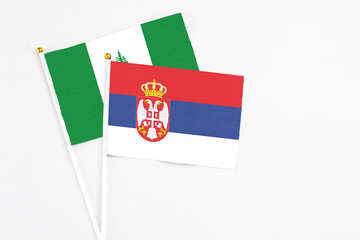 Serbia and Norfolk Island stick flags on white background. High quality fabric, miniature national flag. Peaceful global concept.White floor for copy space.