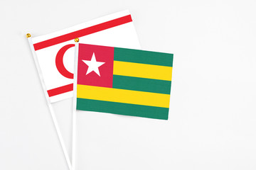 Togo and Northern Cyprus stick flags on white background. High quality fabric, miniature national flag. Peaceful global concept.White floor for copy space.