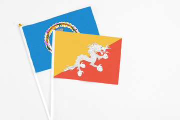 Bhutan and Northern Mariana Islands stick flags on white background. High quality fabric, miniature national flag. Peaceful global concept.White floor for copy space.