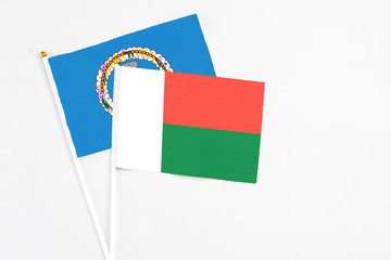 Madagascar and Northern Mariana Islands stick flags on white background. High quality fabric, miniature national flag. Peaceful global concept.White floor for copy space.