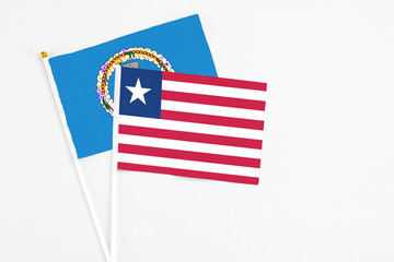 Liberia and Northern Mariana Islands stick flags on white background. High quality fabric, miniature national flag. Peaceful global concept.White floor for copy space.