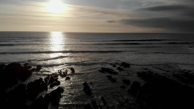 Sun Reflected In Sea West Coast England Aerial View Slow Descend Rocky Beach