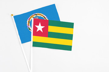 Togo and Northern Mariana Islands stick flags on white background. High quality fabric, miniature national flag. Peaceful global concept.White floor for copy space.