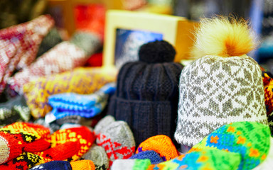 Fototapeta na wymiar Warm hats and other knitted clothes in stalls at Christmas market in Riga of Latvia winter. Europe. Street Xmas and holiday fair in European city or town. Advent Decoration with Crafts Items on Bazaar