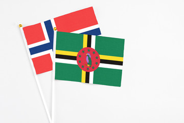 Dominica and Norway stick flags on white background. High quality fabric, miniature national flag. Peaceful global concept.White floor for copy space.