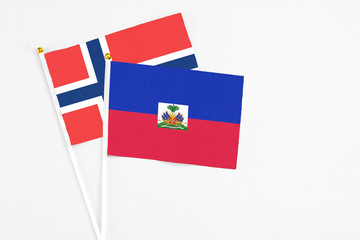 Haiti and Norway stick flags on white background. High quality fabric, miniature national flag. Peaceful global concept.White floor for copy space.