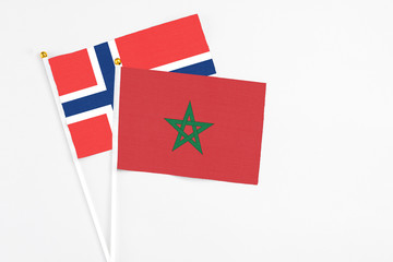 Fototapeta premium Morocco and Norway stick flags on white background. High quality fabric, miniature national flag. Peaceful global concept.White floor for copy space.