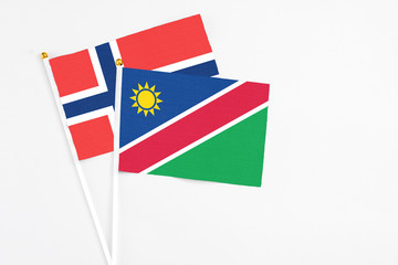 Fototapeta premium Namibia and Norway stick flags on white background. High quality fabric, miniature national flag. Peaceful global concept.White floor for copy space.