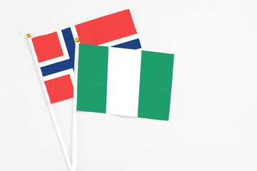 Nigeria and Norway stick flags on white background. High quality fabric, miniature national flag. Peaceful global concept.White floor for copy space.