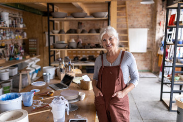Portrait of senior female pottery artist in her art studio - obrazy, fototapety, plakaty