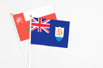 Anguilla and Oman stick flags on white background. High quality fabric, miniature national flag. Peaceful global concept.White floor for copy space.