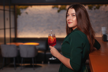 Attractive classy woman having a drink at the bar in the evening