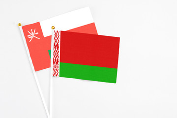 Belarus and Oman stick flags on white background. High quality fabric, miniature national flag. Peaceful global concept.White floor for copy space.
