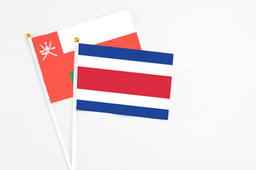 Costa Rica and Oman stick flags on white background. High quality fabric, miniature national flag. Peaceful global concept.White floor for copy space.