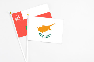 Cyprus and Oman stick flags on white background. High quality fabric, miniature national flag. Peaceful global concept.White floor for copy space.