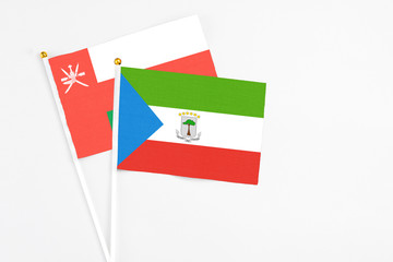 Equatorial Guinea and Oman stick flags on white background. High quality fabric, miniature national flag. Peaceful global concept.White floor for copy space.