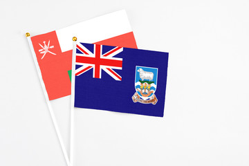 Falkland Islands and Oman stick flags on white background. High quality fabric, miniature national flag. Peaceful global concept.White floor for copy space.