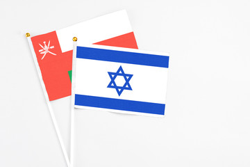 Israel and Oman stick flags on white background. High quality fabric, miniature national flag. Peaceful global concept.White floor for copy space.