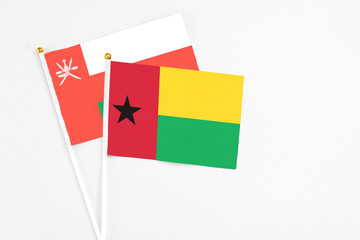 Guinea Bissau and Oman stick flags on white background. High quality fabric, miniature national flag. Peaceful global concept.White floor for copy space.