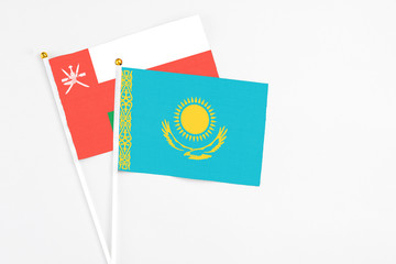 Kazakhstan and Oman stick flags on white background. High quality fabric, miniature national flag. Peaceful global concept.White floor for copy space.