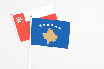 Kosovo and Oman stick flags on white background. High quality fabric, miniature national flag. Peaceful global concept.White floor for copy space.