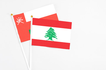 Lebanon and Oman stick flags on white background. High quality fabric, miniature national flag. Peaceful global concept.White floor for copy space.