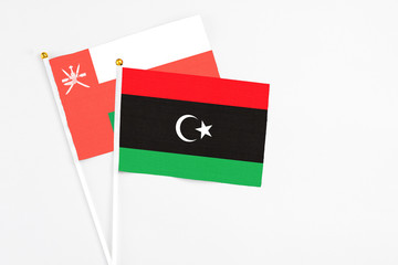 Libya and Oman stick flags on white background. High quality fabric, miniature national flag. Peaceful global concept.White floor for copy space.