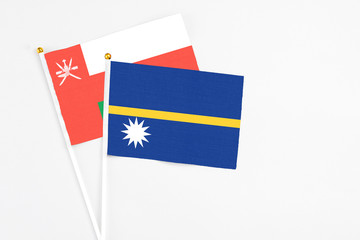 Nauru and Oman stick flags on white background. High quality fabric, miniature national flag. Peaceful global concept.White floor for copy space.