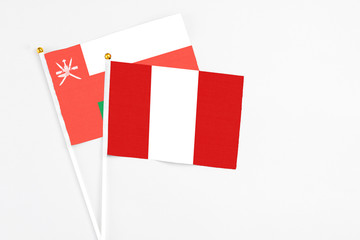 Peru and Oman stick flags on white background. High quality fabric, miniature national flag. Peaceful global concept.White floor for copy space.