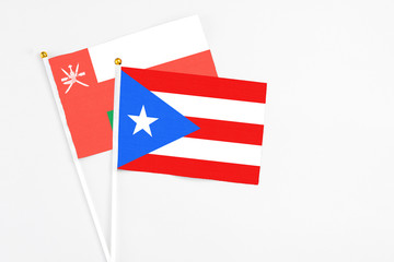 Puerto Rico and Oman stick flags on white background. High quality fabric, miniature national flag. Peaceful global concept.White floor for copy space.