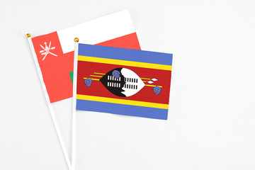 Swaziland and Oman stick flags on white background. High quality fabric, miniature national flag. Peaceful global concept.White floor for copy space.