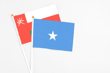 Somalia and Oman stick flags on white background. High quality fabric, miniature national flag. Peaceful global concept.White floor for copy space.