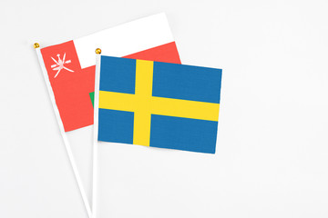 Sweden and Oman stick flags on white background. High quality fabric, miniature national flag. Peaceful global concept.White floor for copy space.