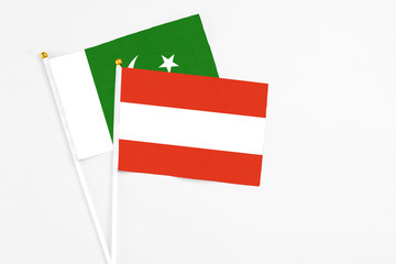 Austria and Pakistan stick flags on white background. High quality fabric, miniature national flag. Peaceful global concept.White floor for copy space.